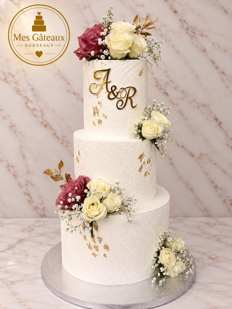 Wedding cake blanc à trois étages avec fleurs et touches dorées