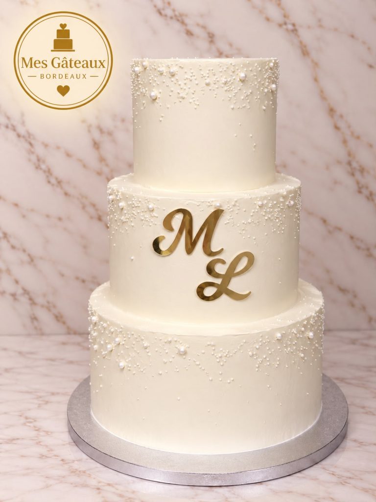 Wedding cake blanc à deux étages décoré d’orchidées et de feuilles dorées